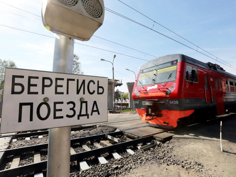 Надпись "Берегись поезда" на фоне железной дороги.